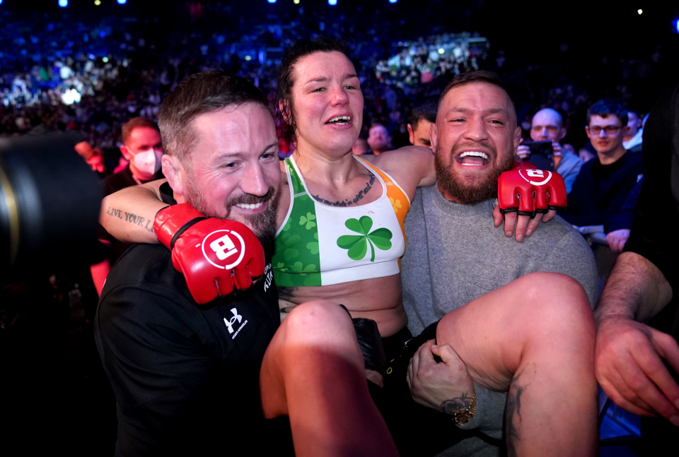 John Kavanagh carrying Sinead Kavanagh out of the cage with Conor McGregor