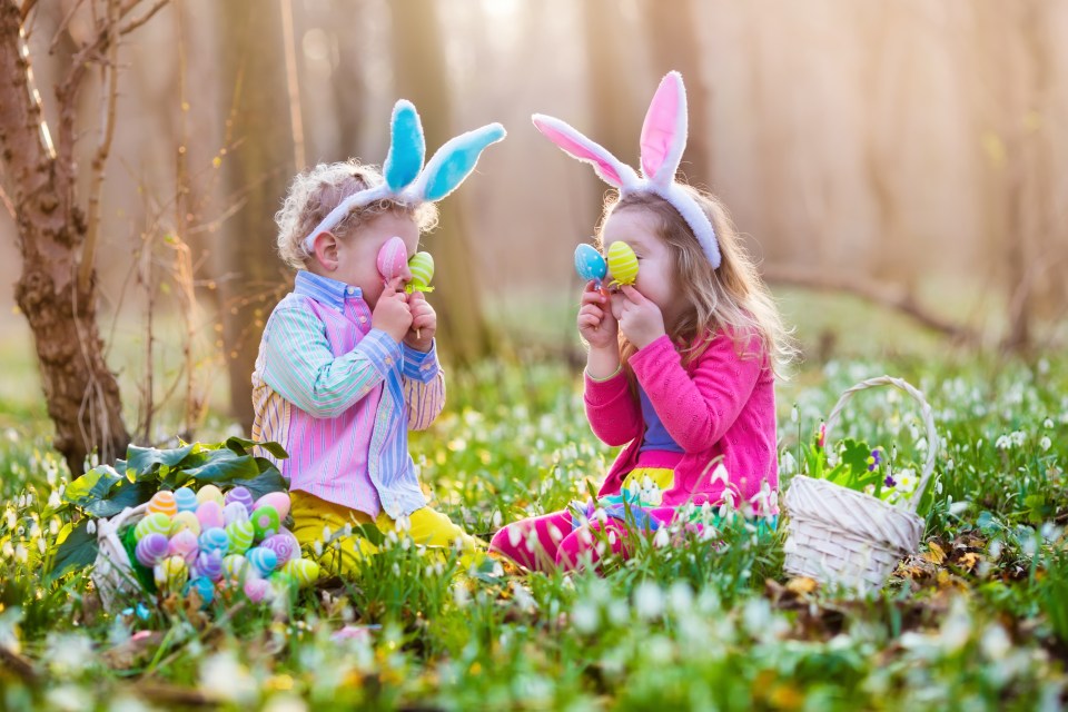 Kids on Easter egg hunt in blooming spring garden