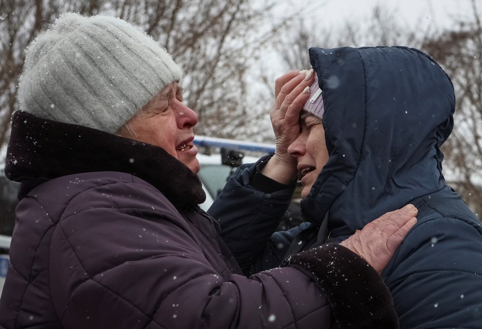 Local residents react near a burnt house in Kharkiv