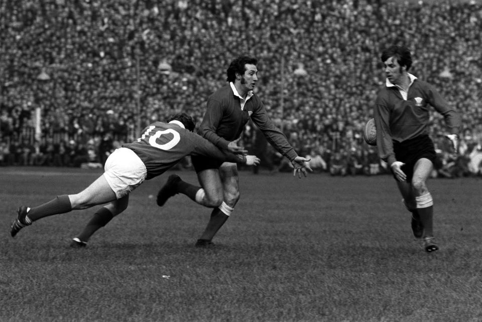 Ireland’s Barry McGann (no.10) tackling Gareth Edwards of Wales, with teammate Barry John to the right