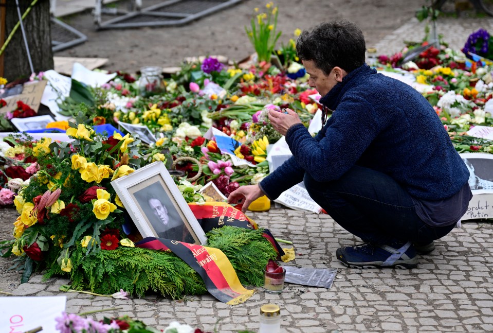 A woman lights a candle at a memorial for Navalny at the Russian embassy in Berlin