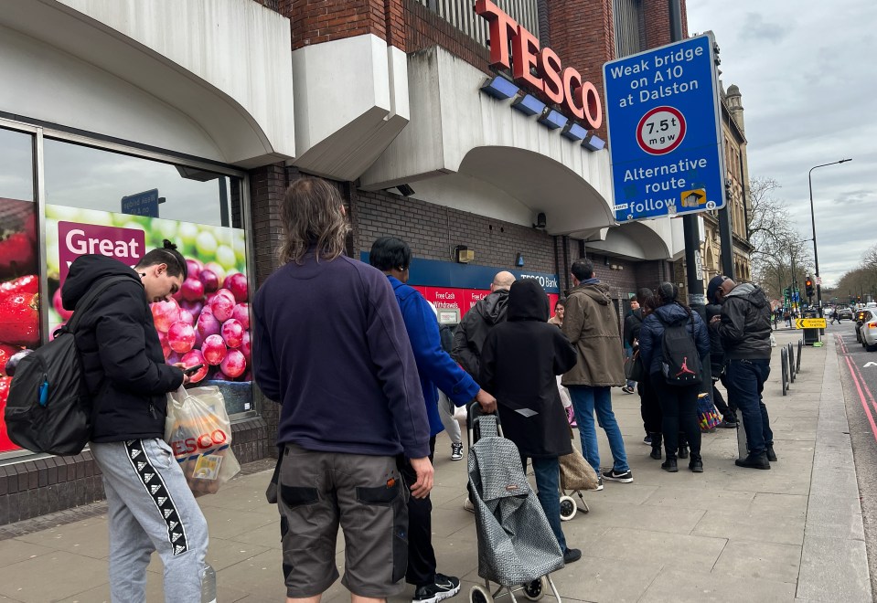 Shoppers queue outside a Tesco store in London to withdraw cash