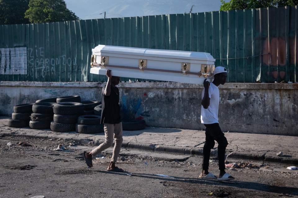 Two men carrying a coffin down a street in Port-au-Prince