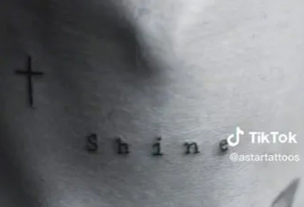 A cross and the word ‘Shine’ appear on the back of his neck