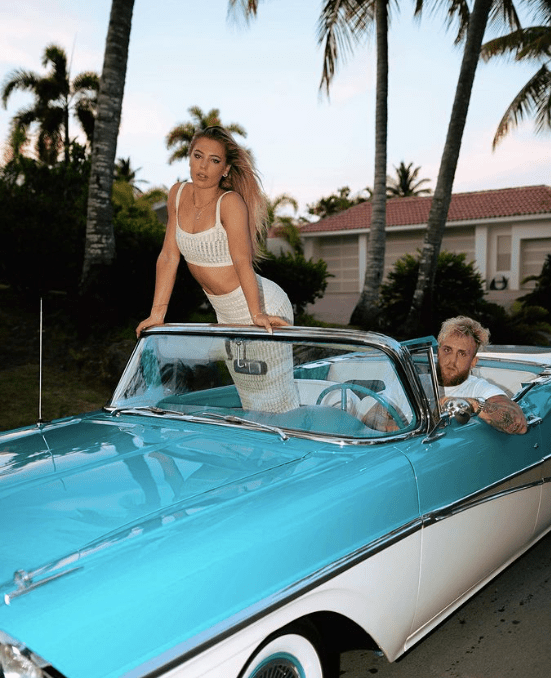 a man and a woman pose in a blue and white car