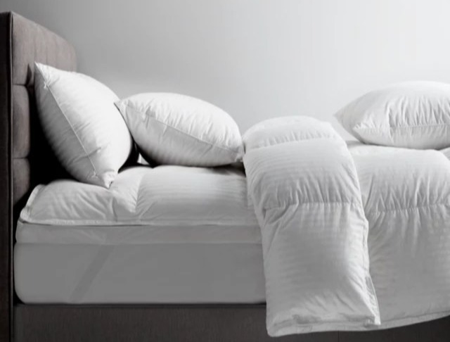 White mattress topper and pillows on a bed.