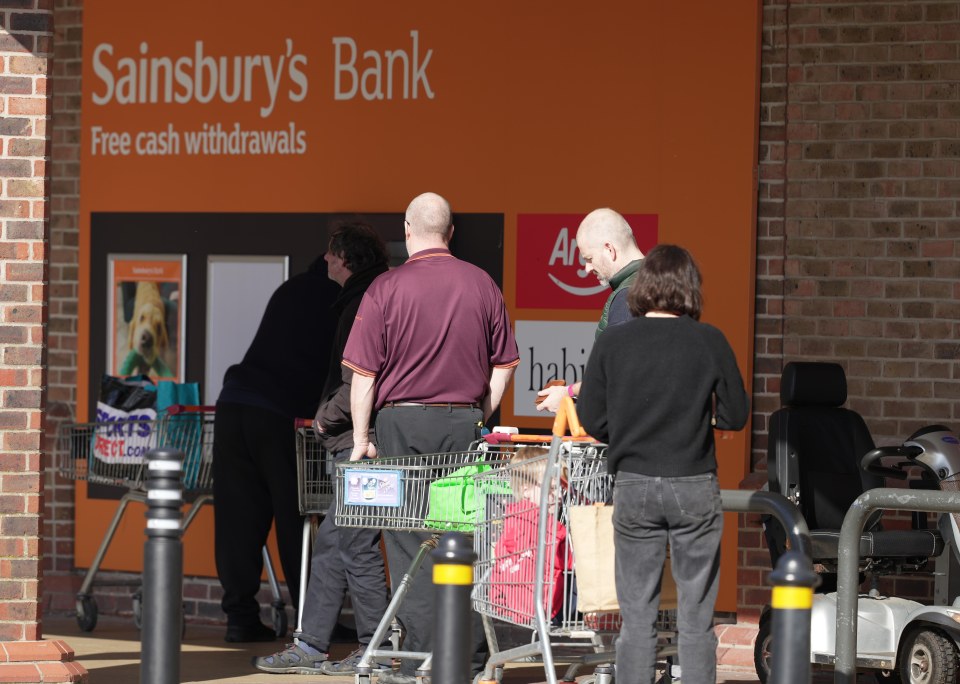 Shoppers at Sainsbury's at Lyons Farm, in Worthing, East Sussex queue up to get cash for their shop