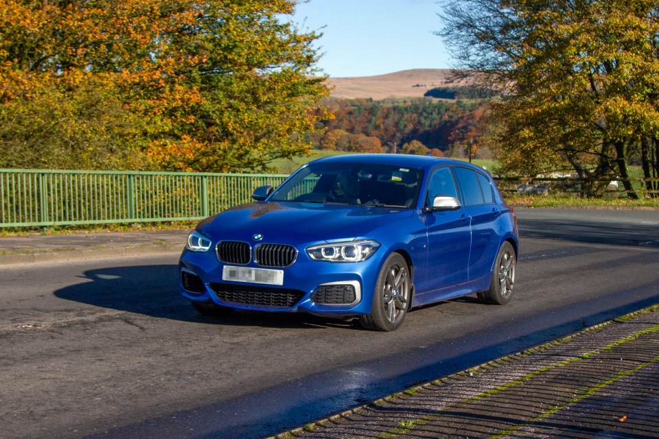 Blue BMW M140i driving across a bridge in Manchester.