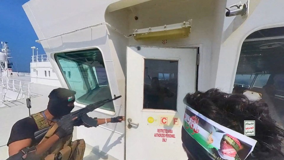 Houthi fighters open the door to the bridge on a ship’s deck in the Red Sea