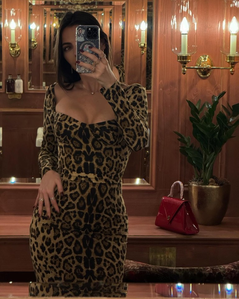 a woman in a leopard print dress takes a selfie in front of a mirror