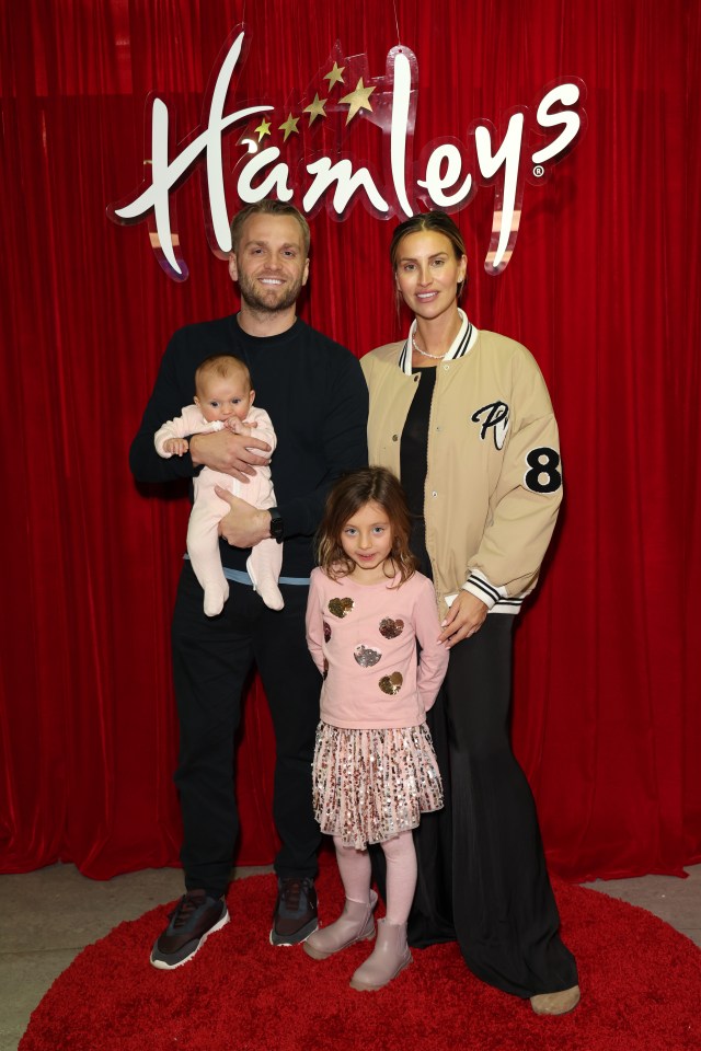 a family poses in front of a hamleys sign