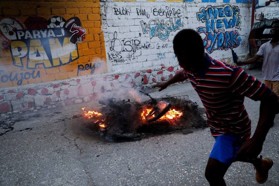 A man runs past the burning belongings and motorbike of murdered gang leader Makandal