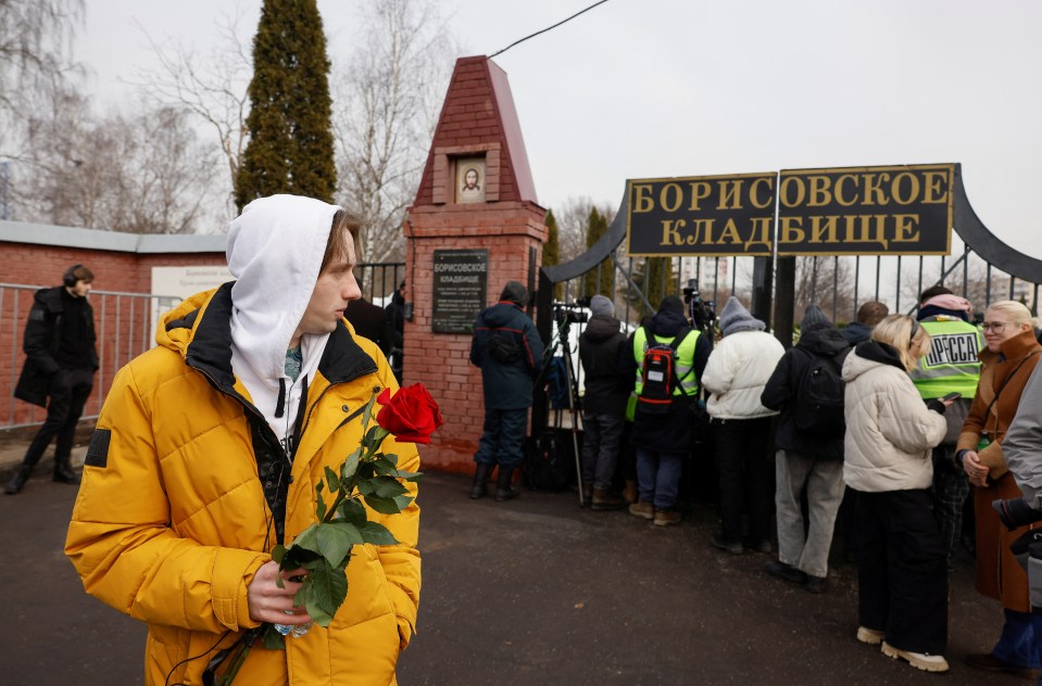 A mourner holds flowers outside the Borisovskoye Cemetery