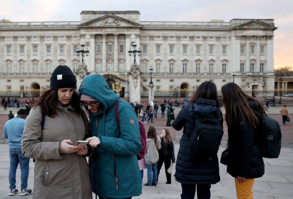 People gather outside Buckingham Palace in London tonight following the announcement