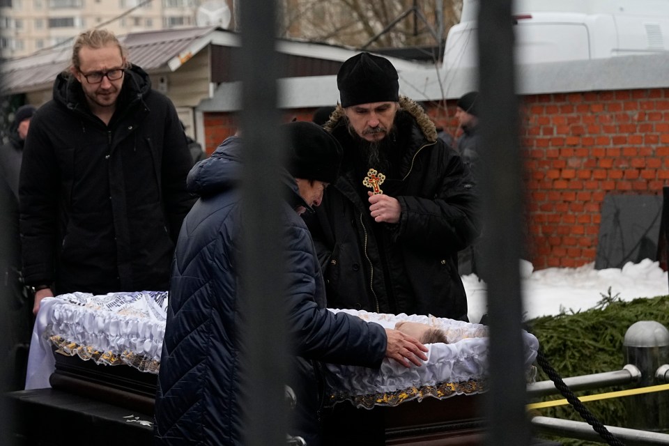 People pay their last respects at the open casket of Navalny before his coffin is lowered into a grave at Borisovo Cemetery