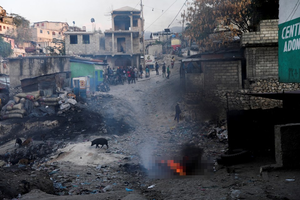 Port-au-Prince residents watch as a body of a suspected gang member burns after vigilantes attacked