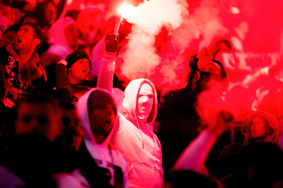 A supporter holds a flare during the Polish PKO Ekstraklasa League match between Legia Warszawa and Warta Poznan