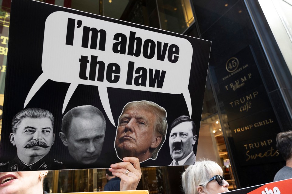 Trump protesters hold a banner and signs at the entrance to Trump Tower last week