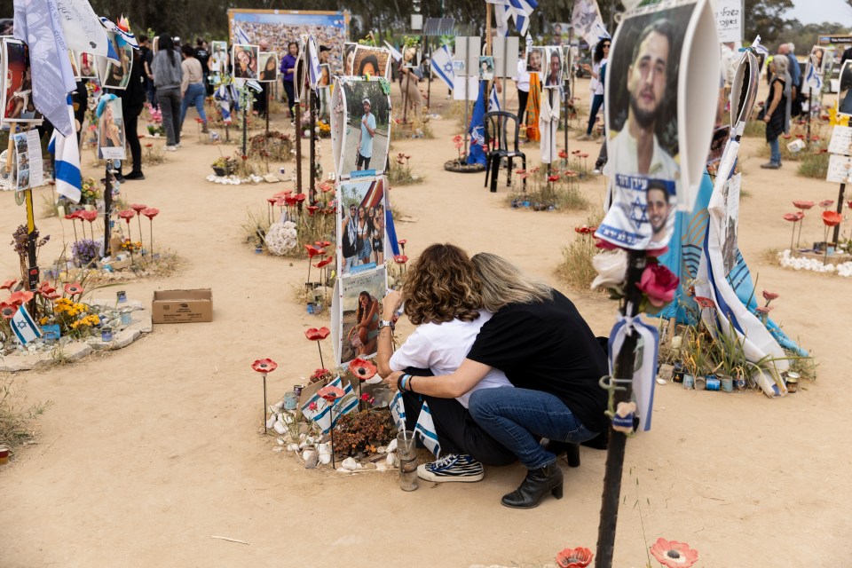 Mourners hug as they sit by the photos of their loved ones