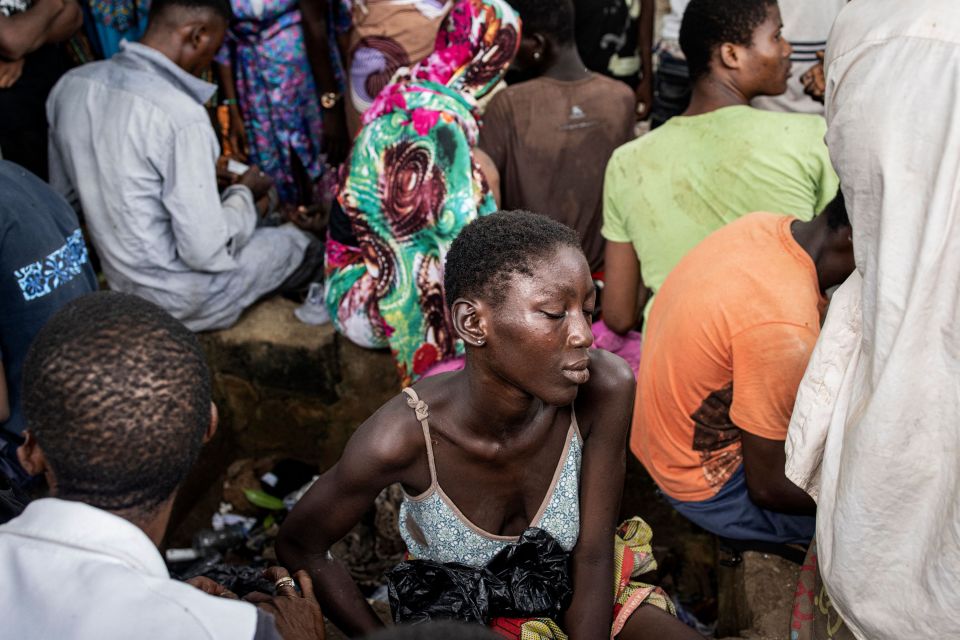 A woman sleeps whilst sitting in a Kush drug den in Freetown