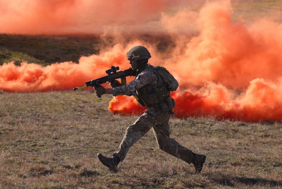 a soldier is running through a field of orange smoke