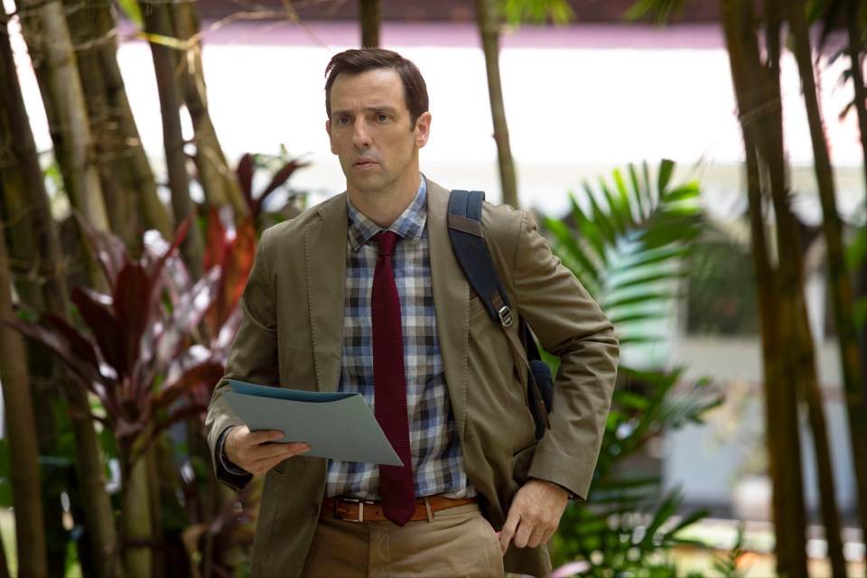 a man in a plaid shirt and tie is holding a piece of paper