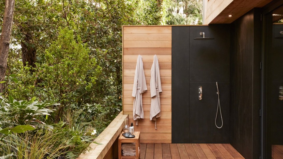 two towels hanging on a wooden wall next to a shower