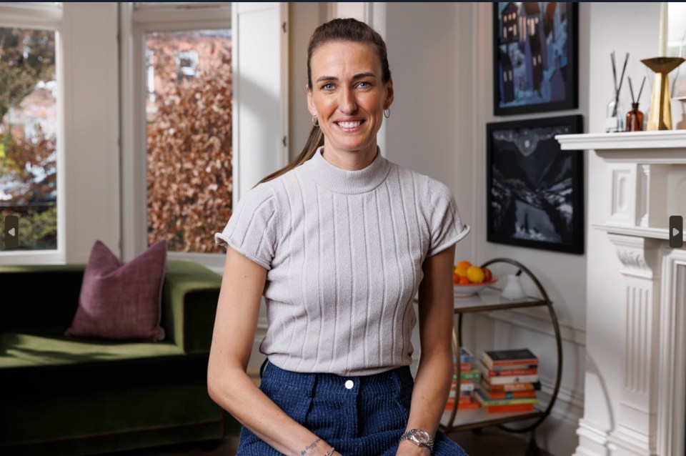 a woman in a grey sweater is smiling in a living room