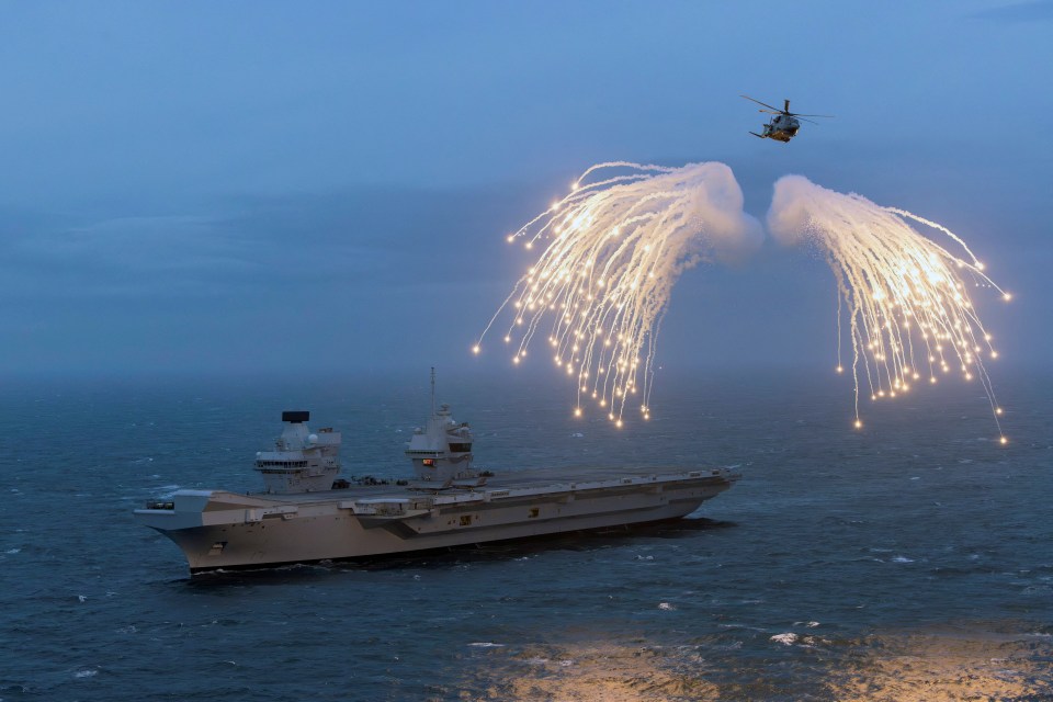 The Royal Navy’s Merlin helicopter from 820 Naval Air Squadron, fires flares above HMS Prince of Wales