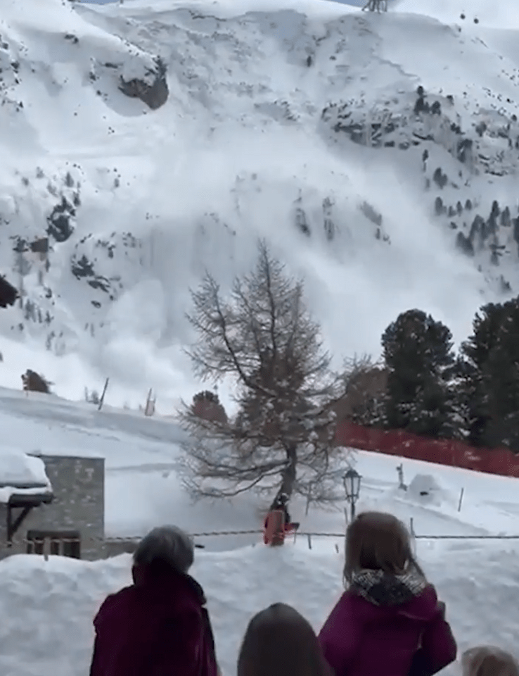 Skiers and holidaymakers watch on as a huge avalanche roars down a Swiss mountain