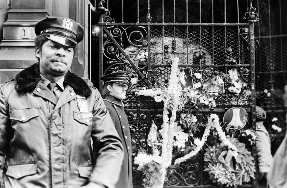 A sombre police officer stands in front of tributes left by fans following Lennon's death