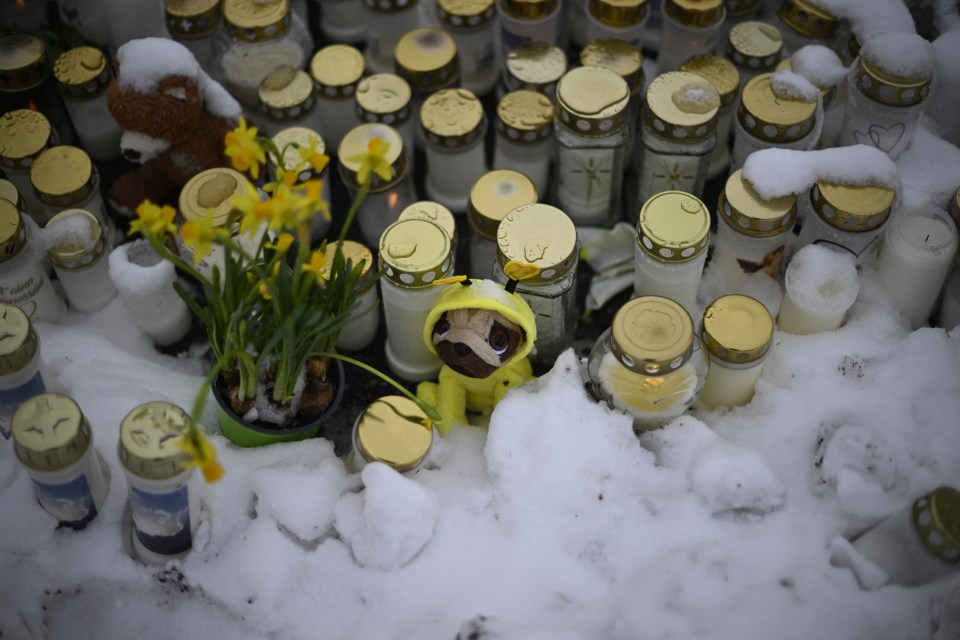 Candles and flowers are placed in the snow in front of the school to pay tribute to the victims