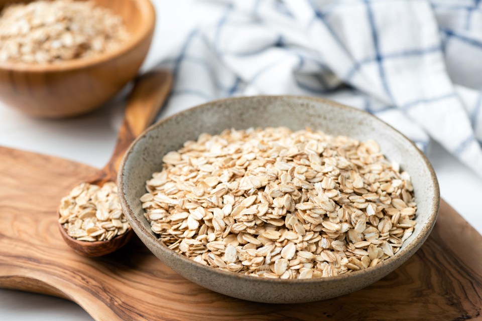 a bowl of oats next to a wooden spoon