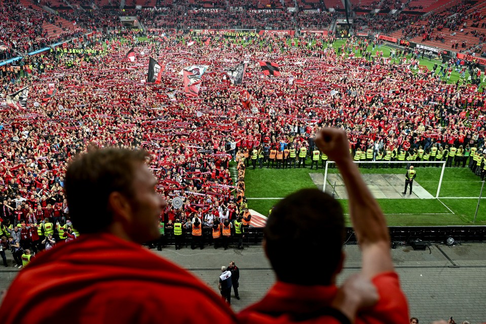 Alonso, right, and Leverkusen sports director Simon Rolfes salute fans