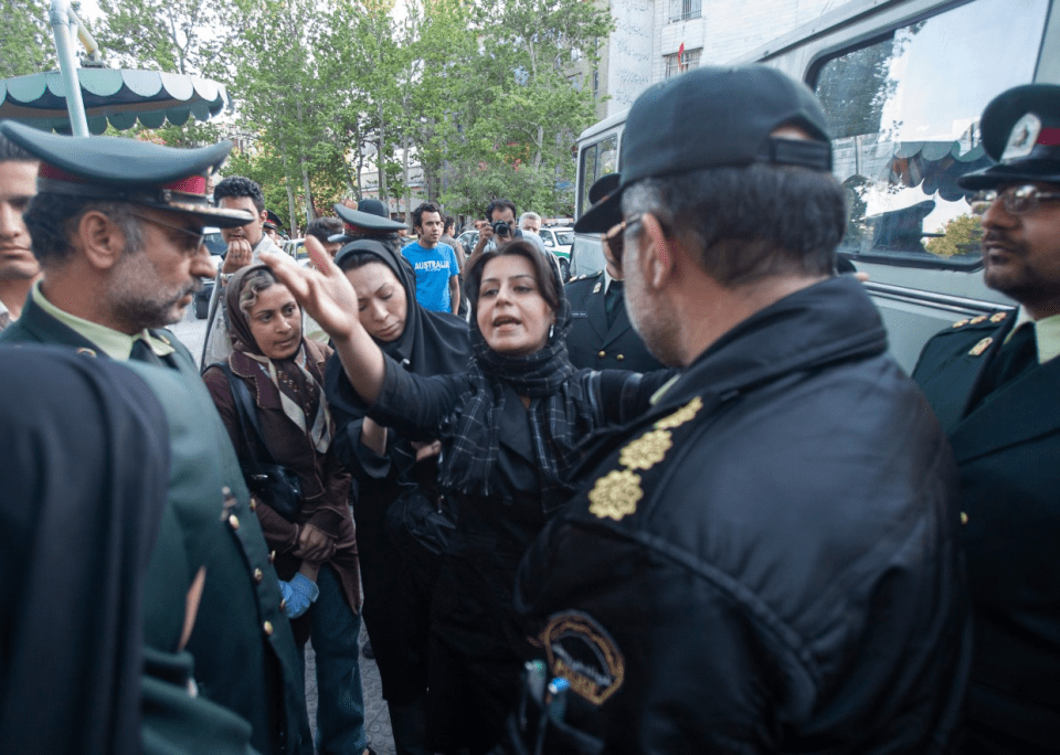 An Iranian woman gestures while talking to two morality policemen in Tehran