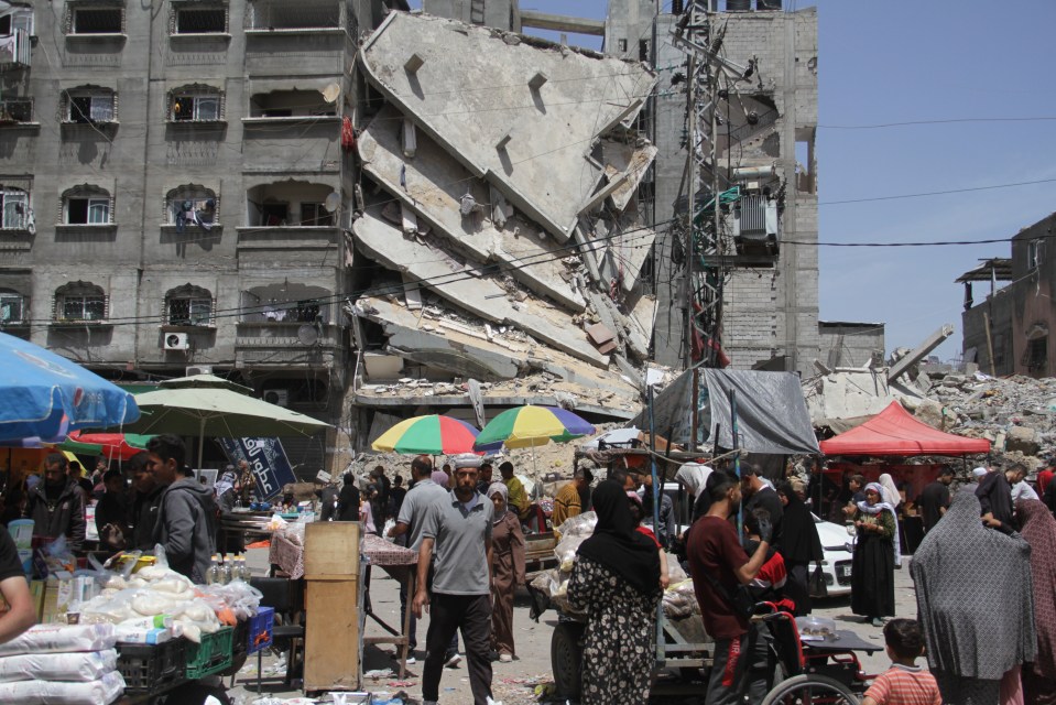 Palestinians trying to shop at a bazaar in between destroyed buildings, April 20