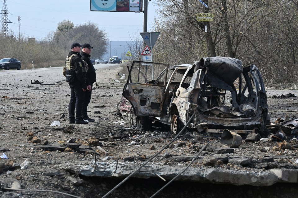 Policemen examine a destroyed car after missiles struck Kharkiv