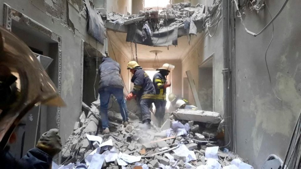 Firefighters rush to a building in the city centre after it was struck by a missile