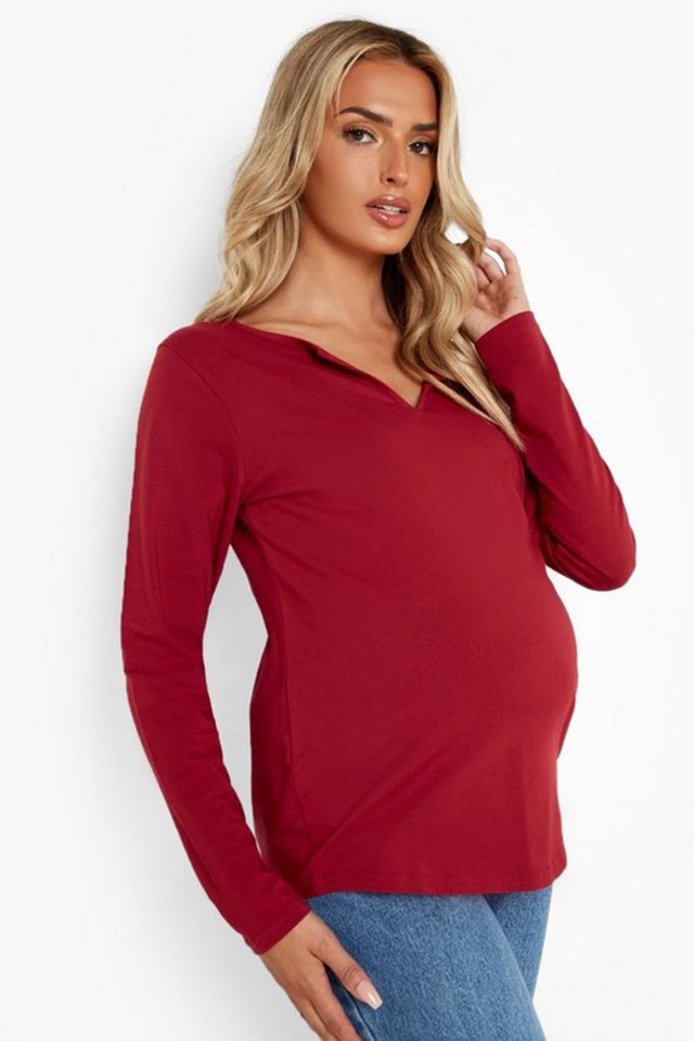 a pregnant woman is wearing a red long sleeve top