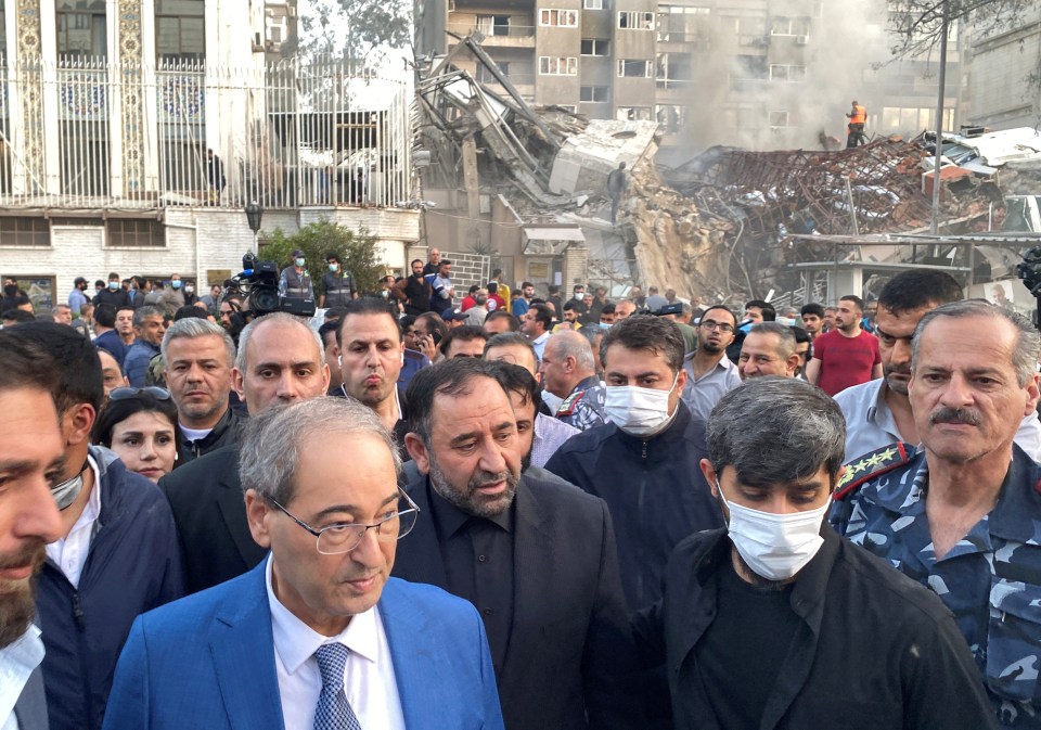 Syrian Foreign Minister Faisal Mekdad walks near a damaged site