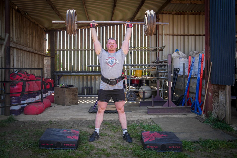 England’s strongest man lifts a barbell made from farm equipment above his head