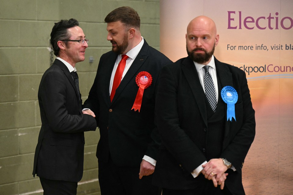 New Labour Party MP for Blackpool South, Chris Webb (C) speaks with acting returning officer Neil Jack (L) as beaten Conservative candidate David Jones (R) looks on at the count centre