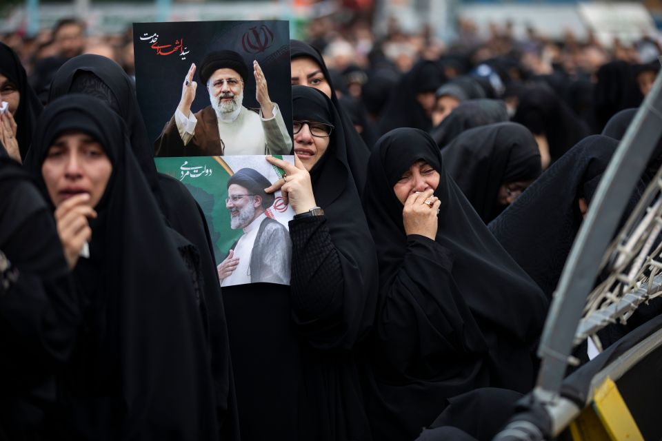 Mourners are seen crying and holding posters of the president