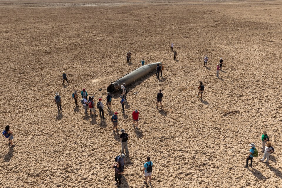 People gather around a component from one of Iran's intercepted ballistic missile that fell near the Dead Sea in Israel last month