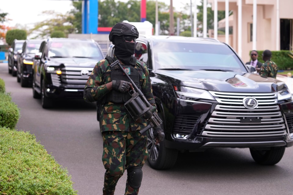 A military officer stand guards in front of a car carrying Prince Harry and Meghan during the visit