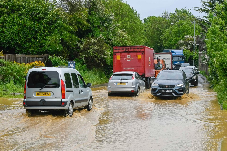 Cars struggled to drive through flooding on the A35 at Winterbourne Abbas in Dorset yesterday