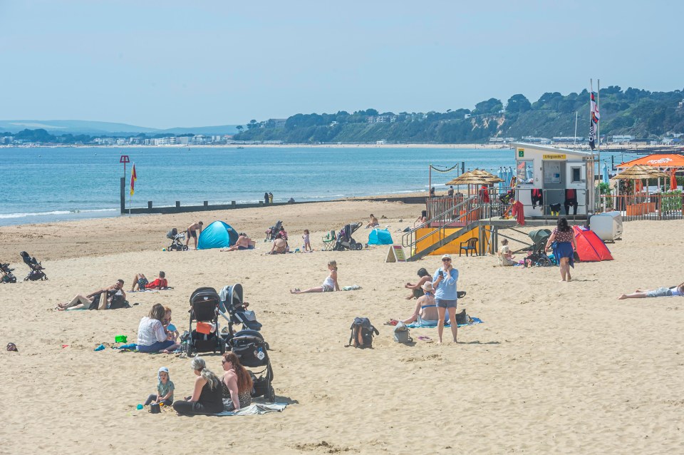 People head to the beach to enjoy the bright sunshine and warm weather in Bournemouth, Dorset