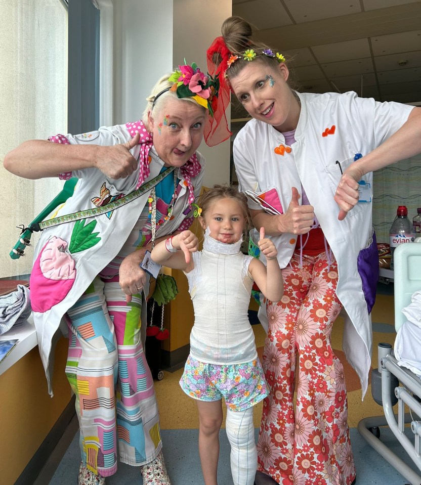 The youngster with play workers at the hospital before her surgeries