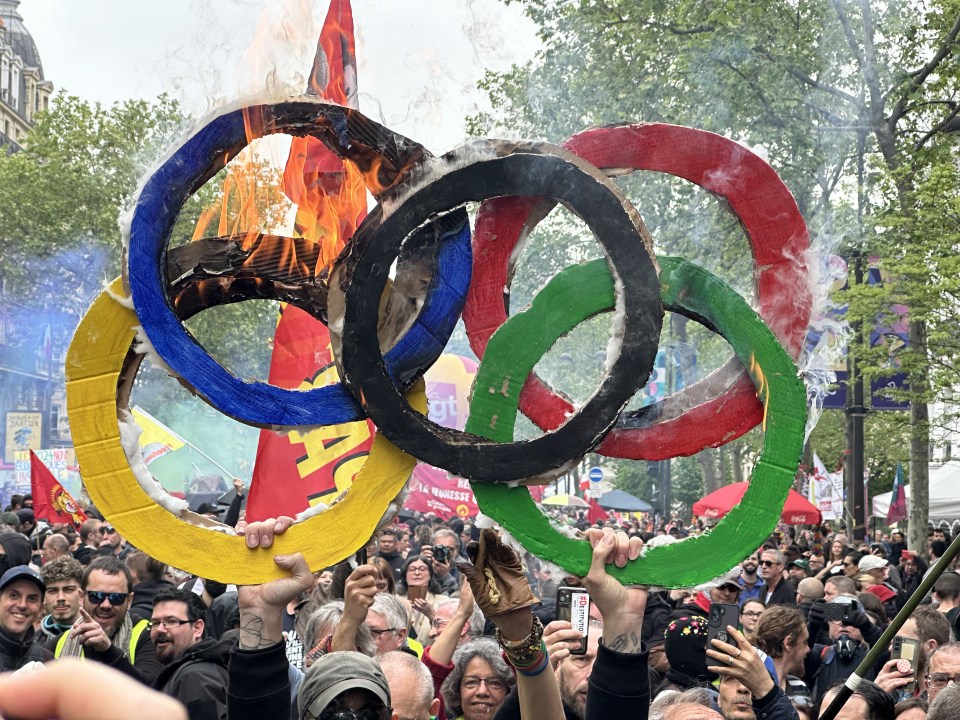 PARIS, FRANCE - MAY 01: Protesters burn the Olympic logo during a demonstration rally on the International Labour Day in Paris, France on May 01, 2024. (Photo by Mohamad Salaheldin Abdelg Alsayed/Anadolu via Getty Images)