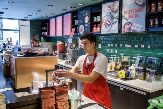 a barista prepares a drink in front of a sign that says celebramos juntos